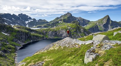 Mountaineer on a rock, mountain landscape with rocky pointed mountain peaks and lakes, with