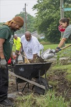 Detroit, Michigan, Volunteers clear weeds and grass in preparation for planting a roadside garden