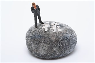 Symbolic photo, man (figure) standing helplessly on a stone with Japanese writing