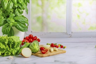 Fresh vegetables on a board, salad ingredients, cucumber, tomatoes, lettuce, basil, pepperoni,