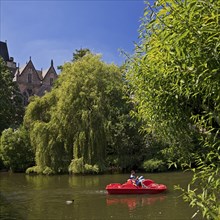 Father and son in a pedal boat on the river Lahn with the Old University in the background,