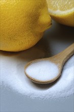 Citric acid in wooden spoon and lemon