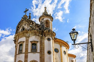 Facade and towers of an old baroque church with a crucifix in the city of Ouro Preto in Minas