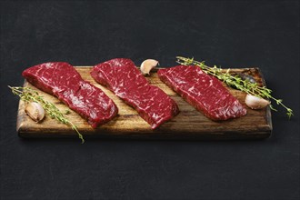 Raw strip steak boneless on wooden cutting board