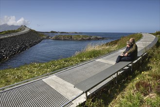 Couple sitting on a bench on the Atlantic Road in Norway