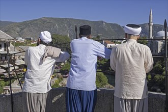 Three Muslim men on the Stari Most, 16th-century Ottoman bridge in the city Mostar,