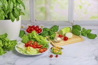 Fresh vegetables on board and plate, salad ingredients, cucumber peeled, tomatoes, lettuce, basil,