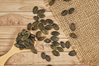 Dark roasted pumpkin seeds without husks on wooden table