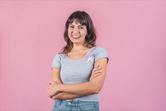 Happy woman wearing a pink breast cancer awareness ribbon while looking at camera