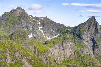 Mountain landscape with steep rocky peaks and waterfall, summit of Hermannsdalstinden, view from