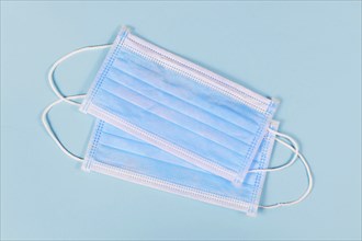 Two disposable medical face masks on blue background