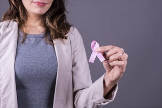 Close-up of a pink badge ribbon holded by a woman to support breast cancer cause