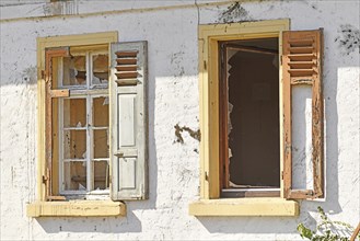 Two old damaged windows with shutters of old abandoned building