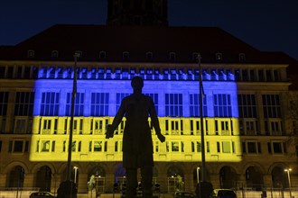 Dresden City Hall illuminated in the Ukrainian national colours, in the foreground the monument to