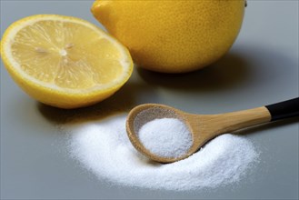 Citric acid in wooden spoon and lemon