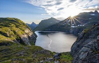 Mountain landscape with lake Tennesvatnet, at sunrise with sun star, Moskenesoya, Lofoten,