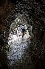 Hiker in a tunnel, Hammersbach flows through Höllentalklamm, near Garmisch-Partenkirchen,