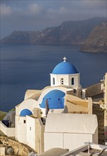 Blue-domed Church of Agios Nikolaos and view of caldera, Ia, Oia, Santorini, Greece, Europe