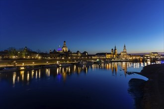 Skyline of Dresden's old town, illuminated in the evening. On the terrace bank on the Elbe, the