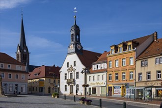 Market square with town hall and historic commercial buildings, including a post office milepost