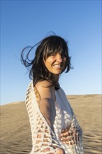 Follow me concept. A smiling long hair woman walking on the sand holding someone's hand