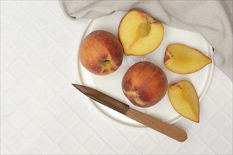 Cut peaches with knife on plate (Prunus persica)