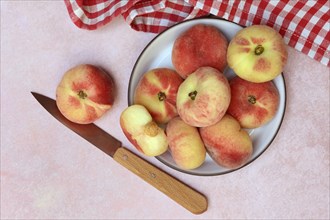 Peach, flat peaches in peel with knife