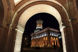 Illuminated church at night with a high tower, blue sky and visible windows. Craiova, Krajowa,