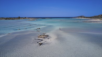 Clear sea water with stones and few people relaxing in the peaceful natural surroundings,