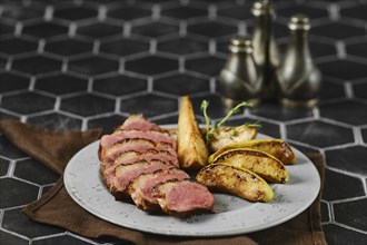 A succulent dish of duck breast, artfully sliced and arranged on a plate with roasted slices of