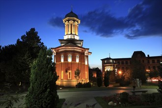 Illuminated church at night with a high tower, blue sky and visible windows. Craiova, Krajowa,