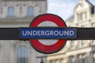 Close-up of a London Underground sign in front of a blurred city background, London, United Kingdom