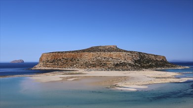 Rocky island with sandbank surrounded by clear blue sea under a cloudless sky, Gramvoussa,