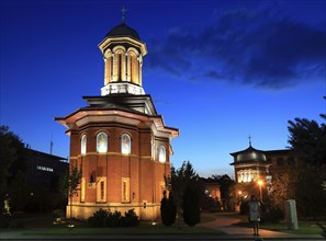 Illuminated church at night with a high tower, blue sky and visible windows. Craiova, Krajowa,