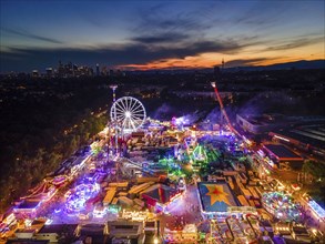 The lights of the Dippemess in Frankfurt am Main glow after sunset. Aerial view, ice rink,