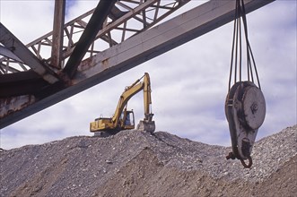 Excvator on top of shingle pile at gold dredge, Westland, New Zealand, Oceania