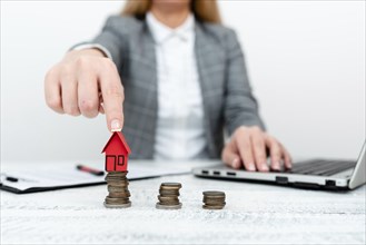 Holding and pointing to house model. Young female holding house over