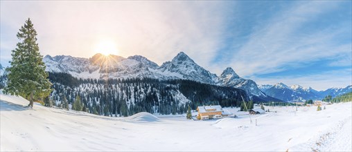 Winter fairytale scenery with a small Austrian village, evergreen fir trees and the Alps covered in