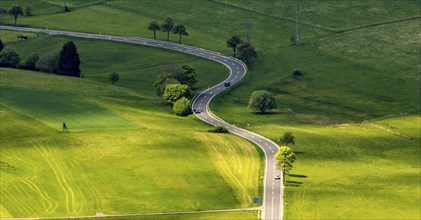 A country road winds through the green landscape of the Voreifel