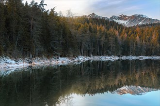 Winter landscape with fir forest and the peaks of Alps mountains reflected in the Eibsee lake, on a