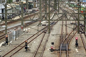 Multiple train tracks, signals and high voltage power lines close to a train station