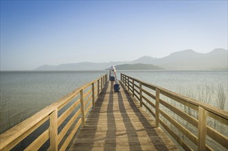 Great vacation concept. Young woman holding her suitcase, waiting for the boat on the dock