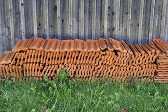 Stacked roof tiles in front of a wooden wall, Germany, Europe