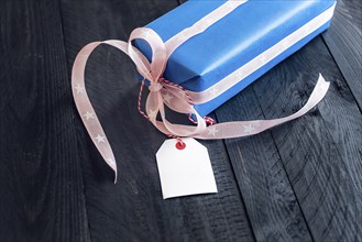 Chic present, wrapped in blue paper and tied with pink ribbon and bow, with an empty label attached