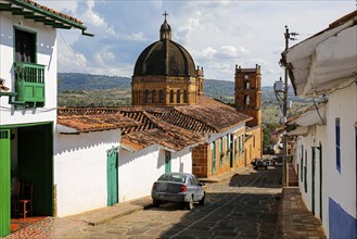 View to a street with typical traditional houses and cathedral in historic town Barichara on a