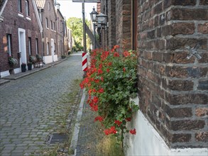 Street scene with a brick facade and flower boxes along a cobblestone street, krudenburg, hünxe,