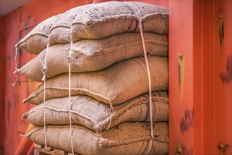 Cropped image with a pile of burlap bags full of goods, stacked on a pallet in a storage and ready