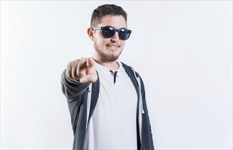 Handsome guy in sunglasses smiling and pointing at the camera isolated