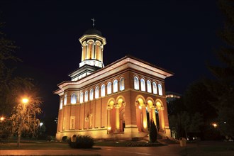 Illuminated church at night with a high tower, blue sky and visible windows. Craiova, Krajowa,