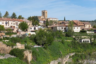 Hilly surroundings with houses and a church tower in the green under a blue sky, city view,